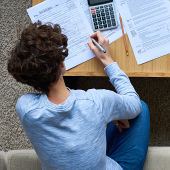 Individual reviews documents on a table with pens and calculator