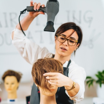 Cosmetology instructor blowdrying a mannequin's hair